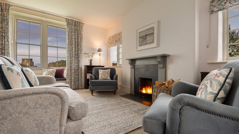 The open-plan sitting and dining room at Carnweather, with open fire and views of Doyden Castle, Cornwall
